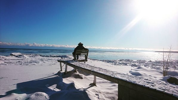 A snowy pier with a bench at the end of it