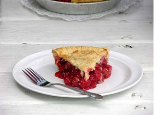 A slice of fresh-baked cherry pie on a wooden table.