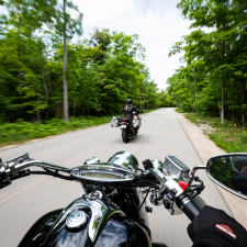Point of view shot of a motorcyclist driving down a road lined with trees.