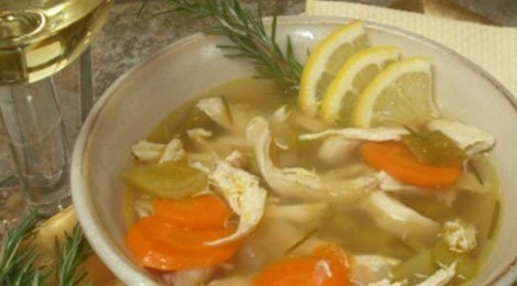 Bowl of chicken soup with sliced lemons in it