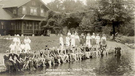 Historic photo of a group of people dipping their feet in the water.