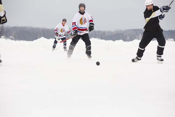 Hockey players fight the puck on a frozen lake.