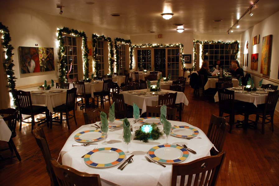A fine-dining restaurant is decorated for Christmas and the tables set for a party.