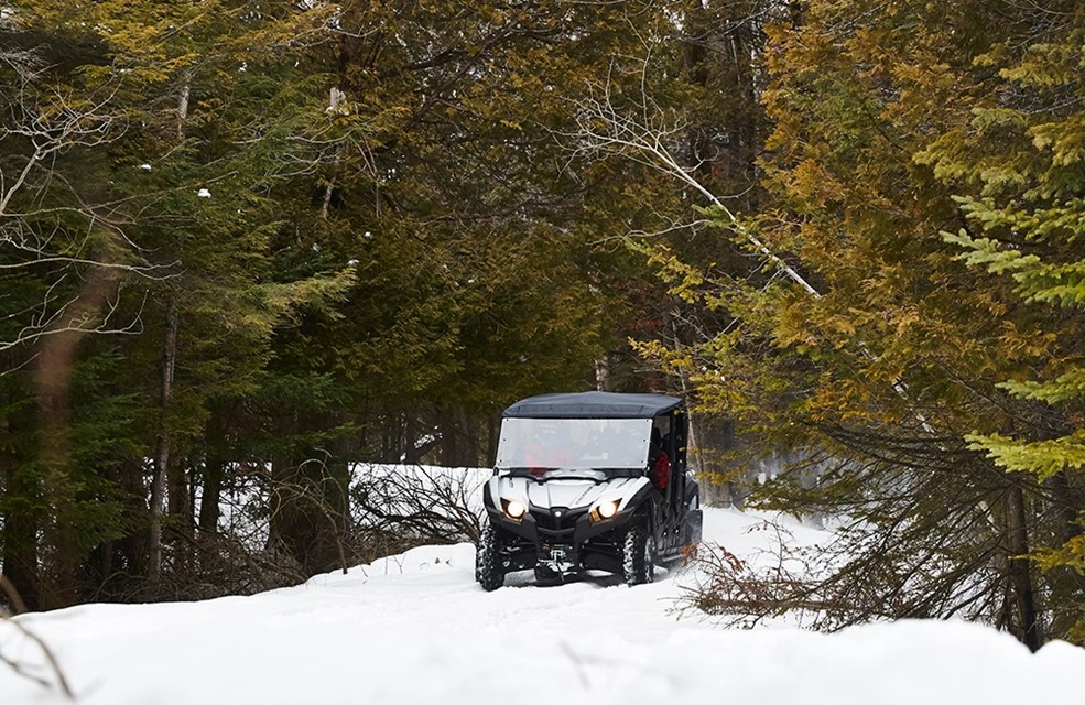 An ATV driving through the snow in the woods.