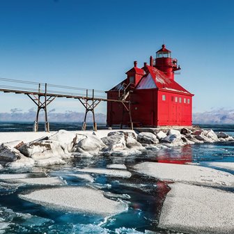 A red lighthouse on a snow-covered point.