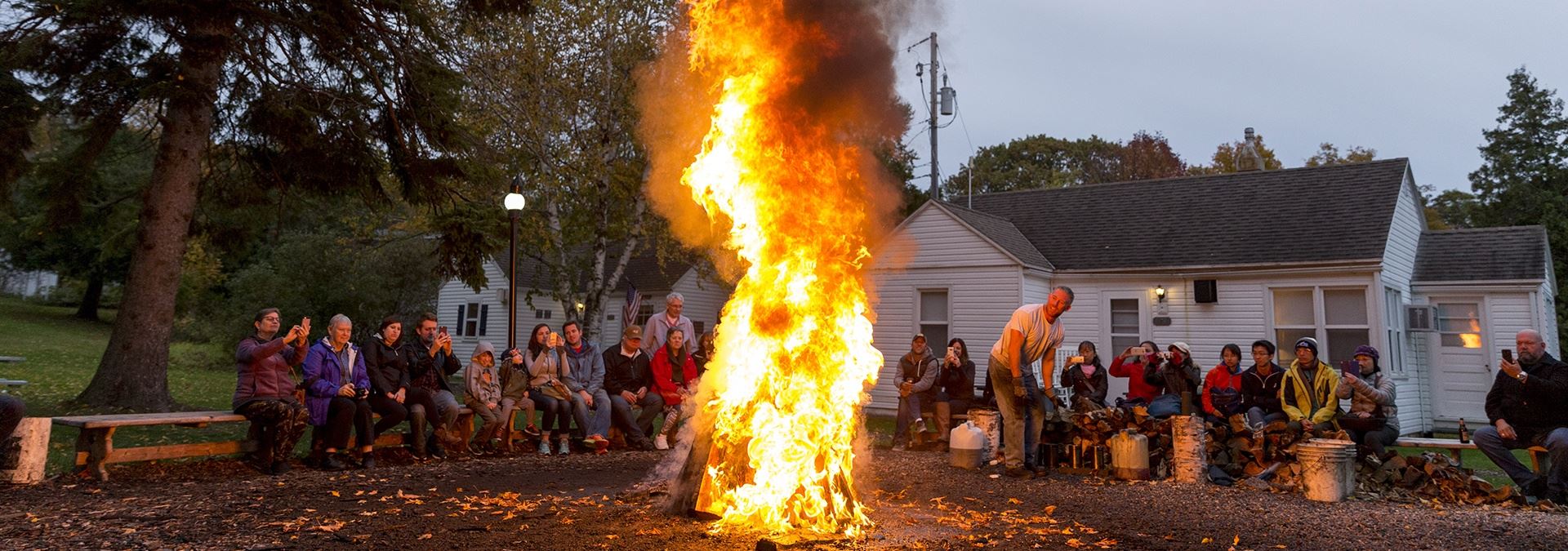 People sitting around a large fire at a fish boil.