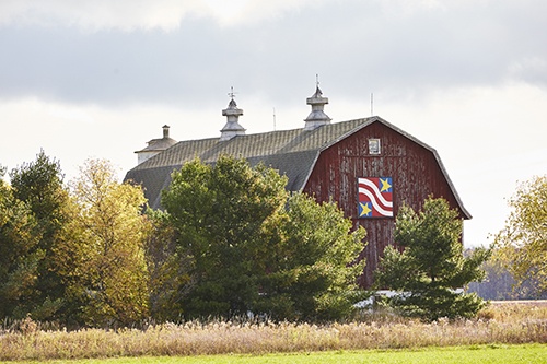 A noble barn in the countryside adorned with a patriotic barn quilt.