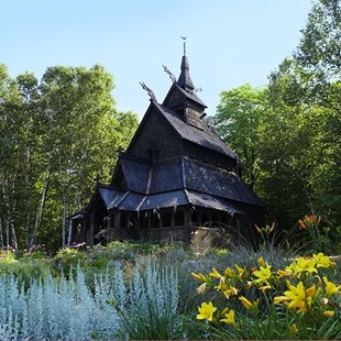 A wooden structure in a clearing surrounded by trees and flowers.