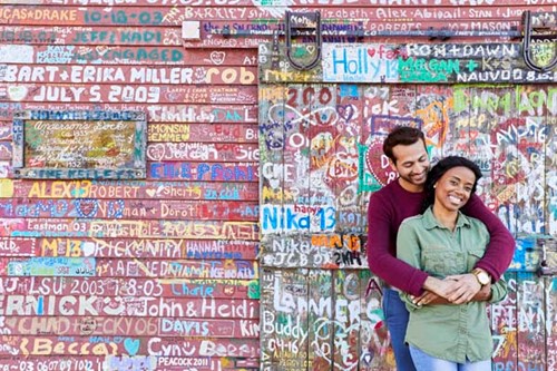 A couple poses in front of the graffiti-covered Anderson Dock, where guests are invited to write their names on the building.