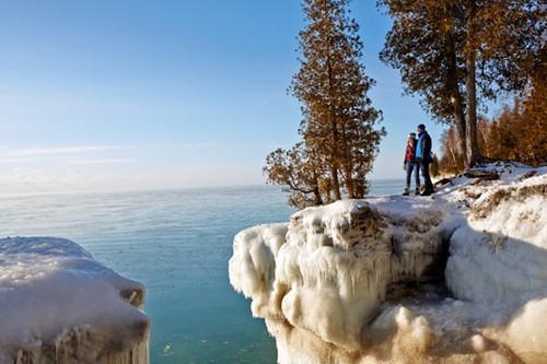 A couple takes in the spectacular winter view at Cave Point.