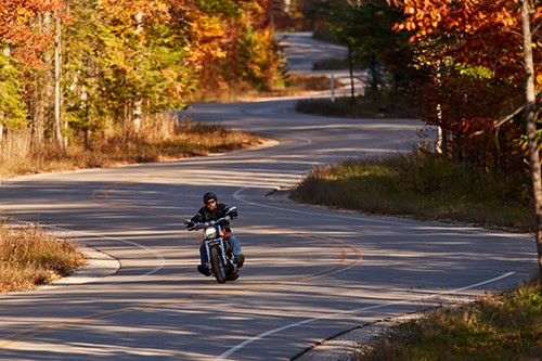 A motorcyclist rides along an empty Hwy. 42 in fall color.