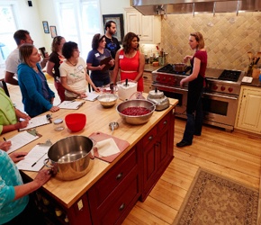Woman teaching a cooking class to students in the kitchen.