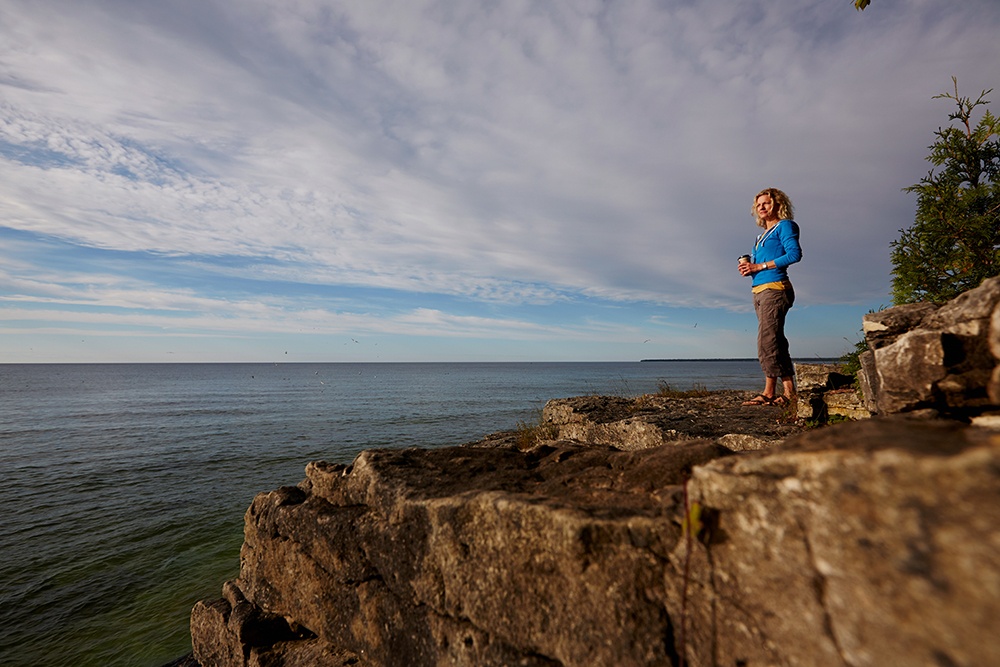 Woman on rock face overlooking water