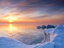 The sun setting beyond the frozen lake.