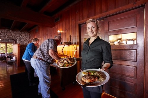 A server at Glidden Lodge shows off hearty plates of steak and fish with sides.
