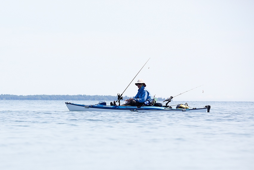 A man fishes from a kayak on an inland lake