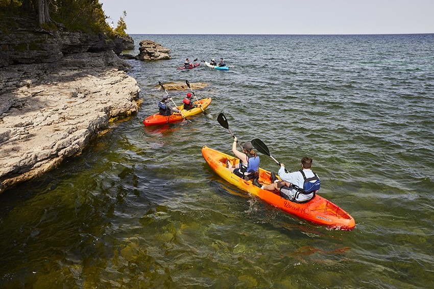 A group of kayakers paddling just off shore.