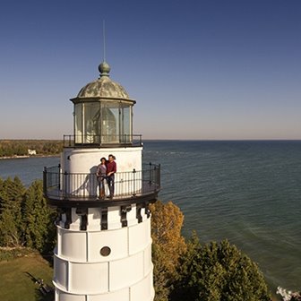 Two people standing on a lighthouse balcony.