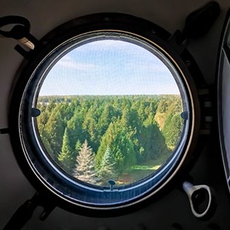 A porthole looking out at trees.