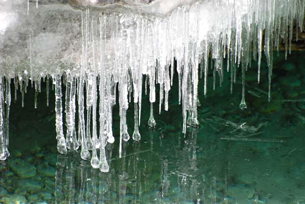 Delicate icicles hanging from cliffs, hanging just over the frozen waterline.