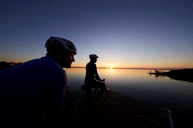 Bikers take in a stunning sunrise from the dock at Anclam Park.