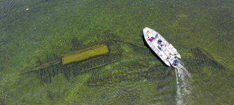 Boat driving above a shipwreck taken from the air.