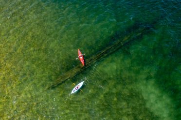 Two kayakers paddle atop a large ship wreck at the bottom of the bay in Door County, WI. 