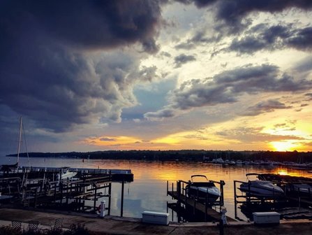 The sun setting over the marina on a cloudy day.