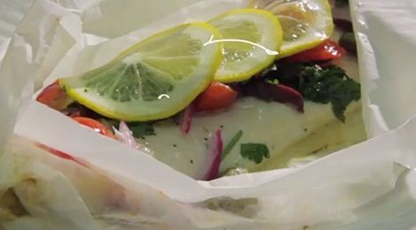 Closeup of a plate of fish with lemon slices on top.