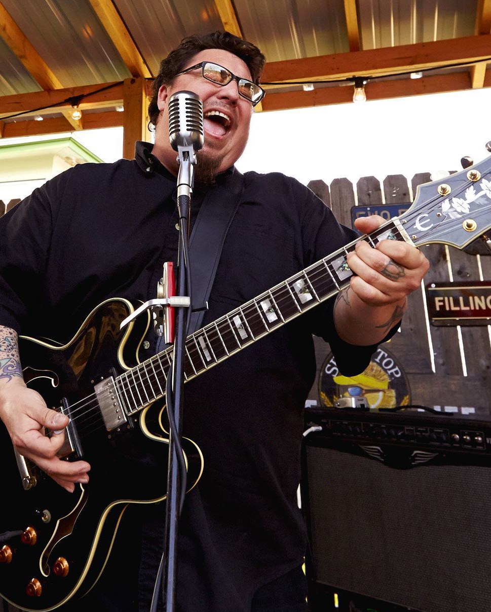 A man singing and playing electric guitar.