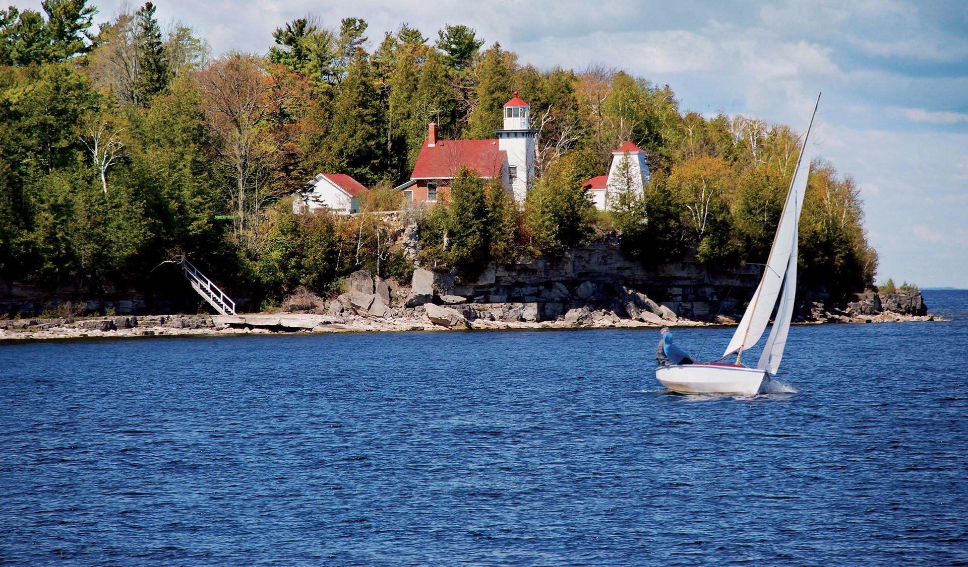 Sailboat in front of lighthouse in the trees