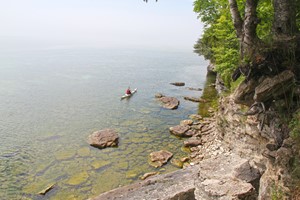 Kayakers paddling along the shoreline and marveling at rock formations