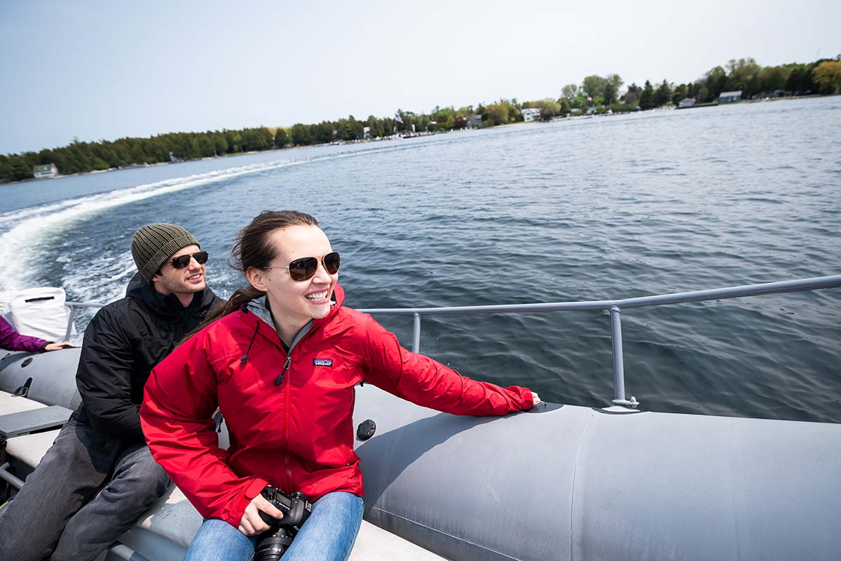 Lakes & Waterways Photo Tour A woman and man ride away from an island on a speeding boat.