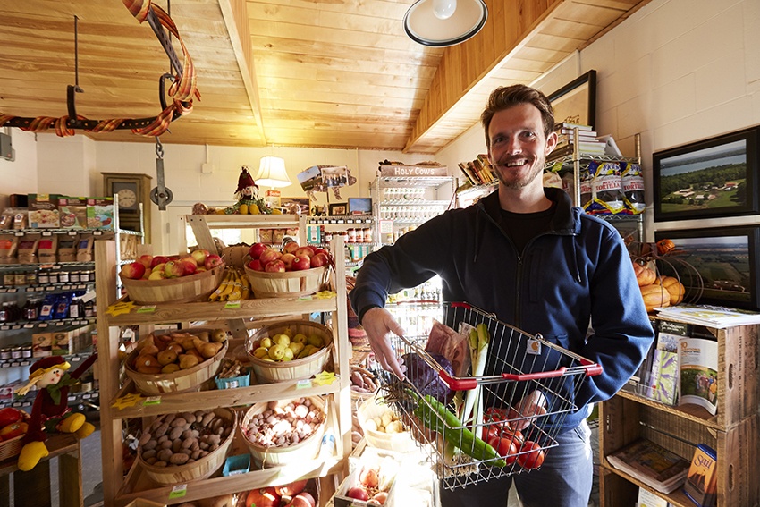 Where to Get Farm Fresh Foods this Season A farmer stands proudly among his produce in a market shop.