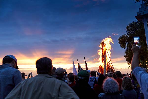 Annual Summertime Events You Can’t Miss A groups watches a massive beach bonfire in awe at the Fyr Bal Festival.