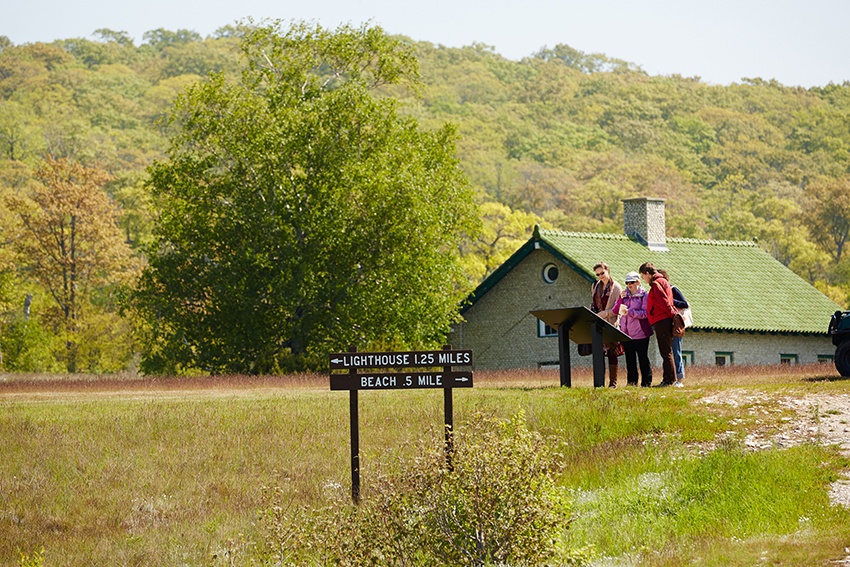Geocaching: Naturalist Treasure Hunting Friends search for geocaches along a meadow trail