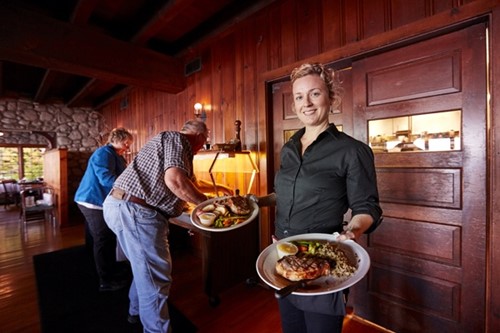 Supper Clubs: A Wisconsin Tradition A server at Glidden Lodge shows off hearty plates of steak and fish with sides.