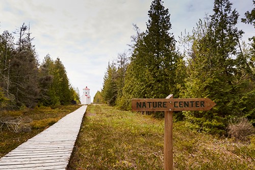 Community Spotlight: Baileys Harbor A hiking trail at The Ridges with a sign pointing to the nature center.