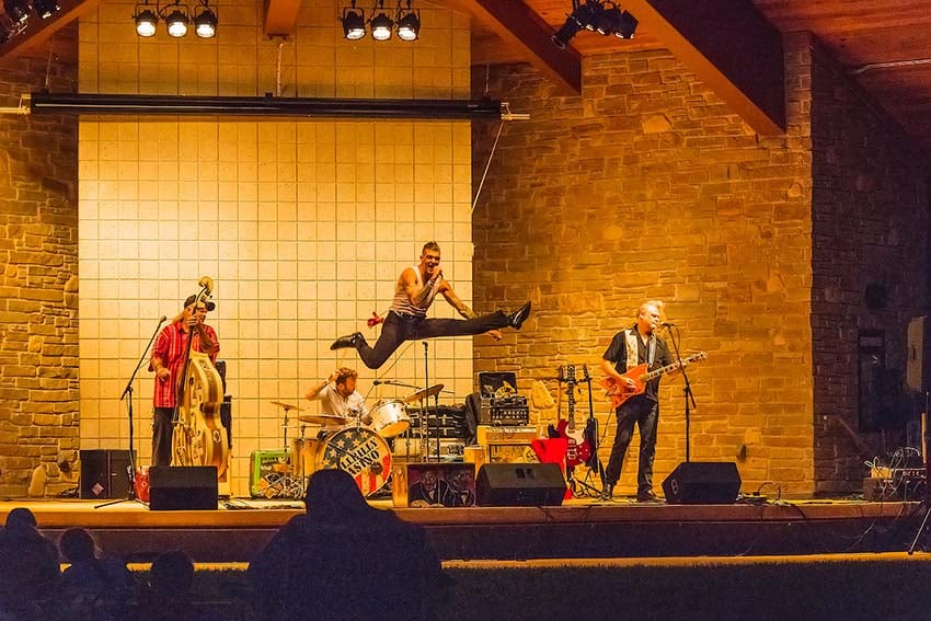 Where to Find Live Music this Summer A high-energy rock band plays on stage at night.