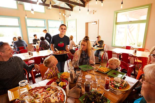 Kids' Favorite Dining & Sweet Treat Spots A family with kids dines on pizza at Wild Tomato.