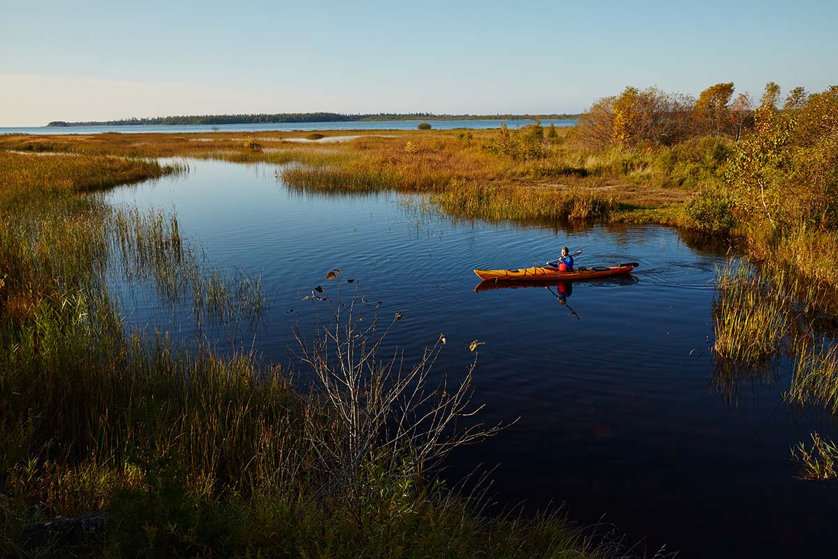 Lakes & Waterways Photo Tour A kayaker floats on a peaceful creek at sunrise in early fall.