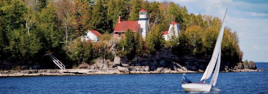 A lighthouse with a sailboat in the foreground