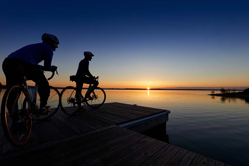 Eco-Friendly Travel People biking by the lake at sunset