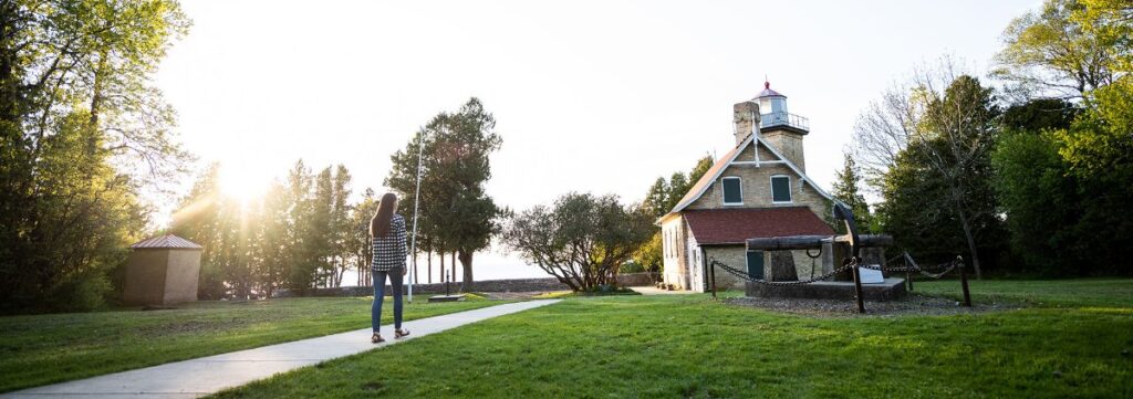 A woman walking toward a building and lighthouse