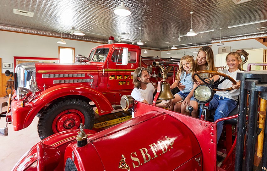 Historical Museums A family sitting in an old fire truck in a museum.