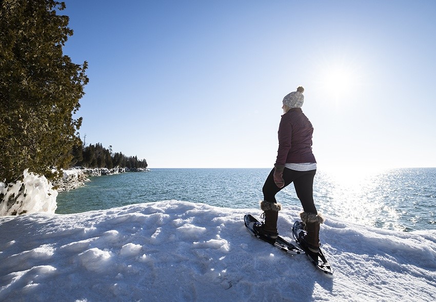 Snowshoeing A snowshoer standing and looking out over the lake.
