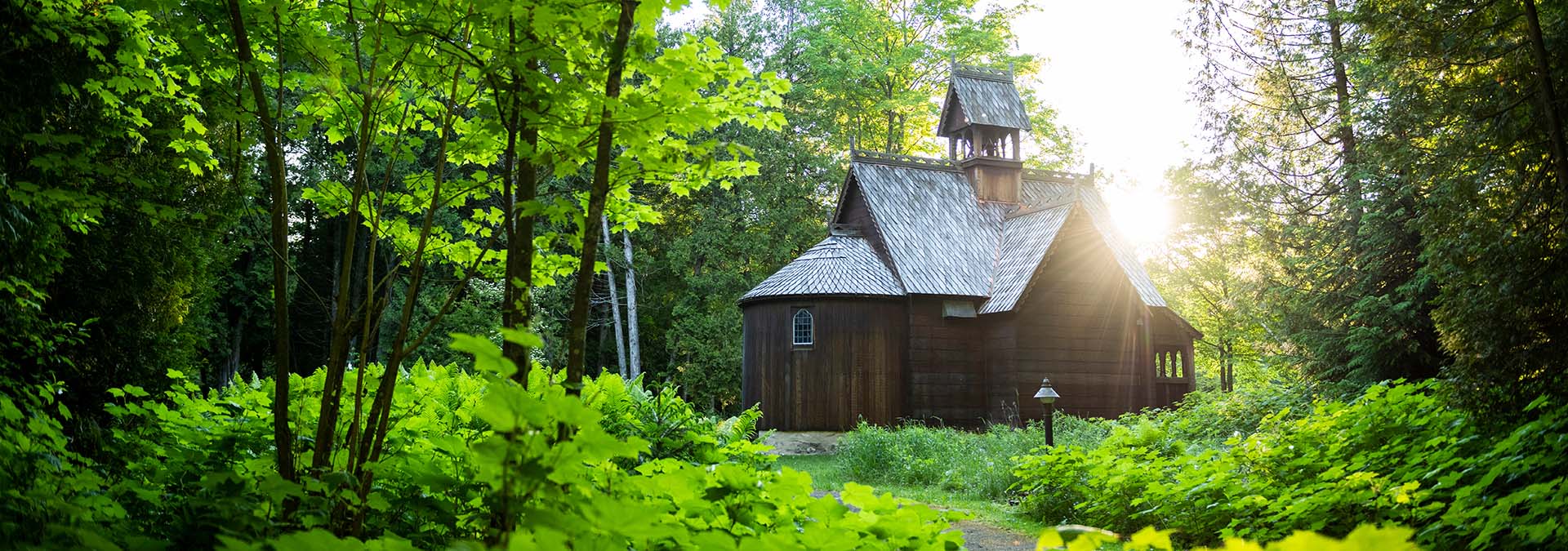 Houses of Worship Wooden church surrounded by trees.