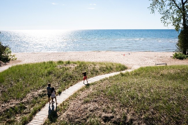People walking on a boardwalk down to the beach.