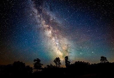Northern Lights in Door County The Milky Way above silhouetted trees.