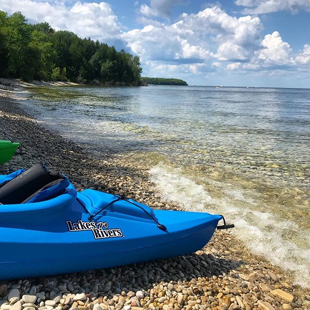 A close up of the side of the front of a kayak on the beach near the water